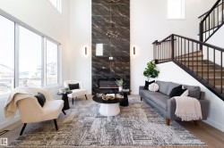 Living room with a high ceiling, wood finished floors, and a premium fireplace - 