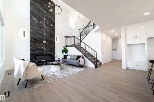 Living area with a high ceiling, a fireplace, light wood-style floors, and a chandelier - 33 Sun Meadows Cl, Stony Plain, AB - Indoor With Fireplace