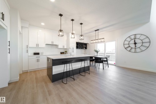 Dual tone kitchen with pendant lighting, two tone cabinets, a breakfast bar area, tasteful backsplash, and an island with sink - 33 Sun Meadows Cl, Stony Plain, AB - Indoor Photo Showing Kitchen With Upgraded Kitchen