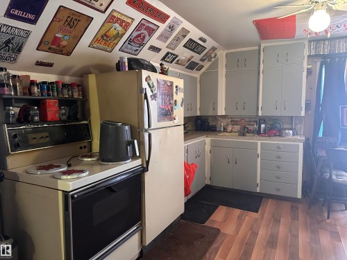 Kitchen featuring wood-finish flooring, light grey cabinetry with white trim, and a built-in oven with an integrated stovetop - 10528 100 Avenue, Westlock, AB - Indoor Photo Showing Laundry Room