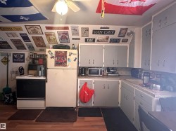 Kitchen area featuring wood-finish flooring, a ceiling fan with integrated lighting, and light grey cabinetry with silver-tone hardware - 