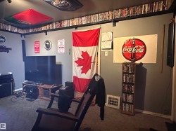 Carpeted room featuring a media console with a television, a built-in shelf above, and a wall-mounted Coca-Cola sign - 