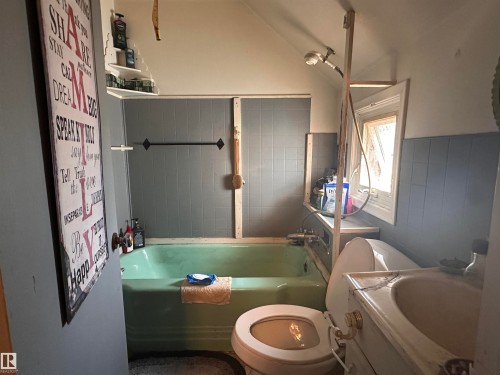Bathroom featuring a green bathtub, porcelain toilet, and a vanity with an integrated sink - 10528 100 Avenue, Westlock, AB - Indoor Photo Showing Bathroom
