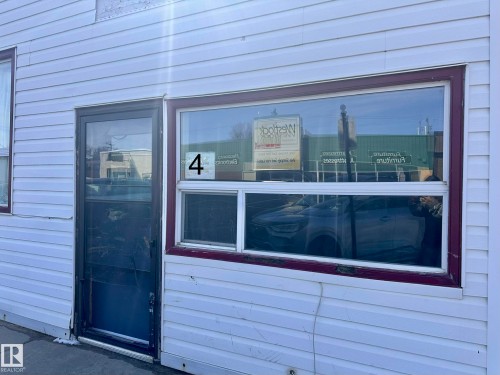 White horizontal siding exterior with a full-light entry door and multi-pane display window - 10528 100 Avenue, Westlock, AB - Outdoor