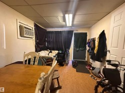 Room featuring wood-finish flooring, a wall-mounted air conditioning unit, and a drop ceiling - 