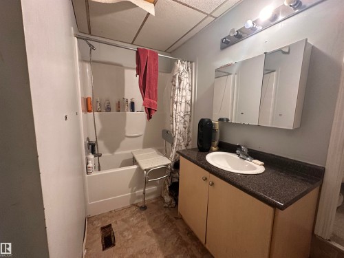 Bathroom featuring a white tub, shower fixture, a single vanity with a built-in sink, and a mirrored medicine cabinet - 10528 100 Avenue, Westlock, AB - Indoor Photo Showing Bathroom