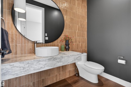 Floating vanity with a stone countertop, vessel sink, and large circular mirror - 149 Eastgate Way, St. Albert, AB - Indoor Photo Showing Bathroom