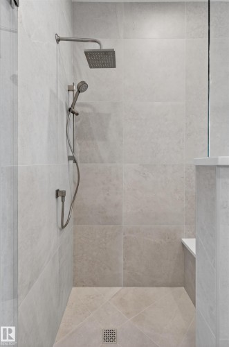 Walk-in shower with large format wall and floor tiling, brushed nickel fixtures, a square rain showerhead, and a handheld shower attachment - 149 Eastgate Way, St. Albert, AB - Indoor Photo Showing Bathroom