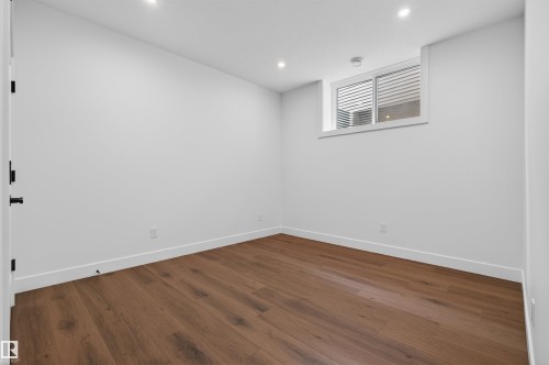 Room featuring wood-finish flooring, recessed ceiling lights, white trim, a window with horizontal blinds, and a white interior door with black hardware - 149 Eastgate Way, St. Albert, AB - Indoor Photo Showing Other Room