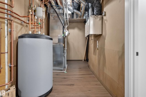 Dedicated utility space featuring a water heater with extensive copper plumbing, forced air furnace, and wood-finish flooring - 149 Eastgate Way, St. Albert, AB - Indoor Photo Showing Basement