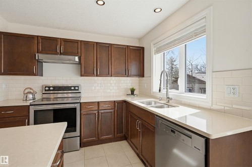 Kitchen featuring dark wood cabinetry, light-toned countertops, and a subway tile backsplash - 11539 75 Avenue, Edmonton, AB - Indoor Photo Showing Kitchen With Double Sink