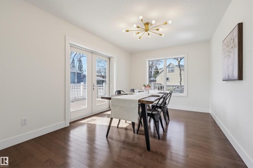 Dining area featuring wood-finish flooring, a contemporary sputnik chandelier, and expansive glass doors opening to an exterior deck - 11539 75 Avenue, Edmonton, AB - Indoor Photo Showing Dining Room