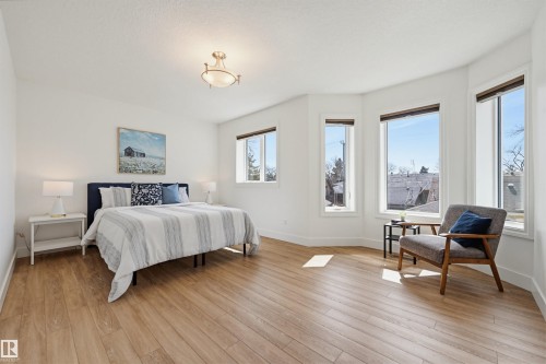 Spacious room featuring light wood-finish flooring, white walls, and a multi-window bay area - 11539 75 Avenue, Edmonton, AB - Indoor Photo Showing Bedroom
