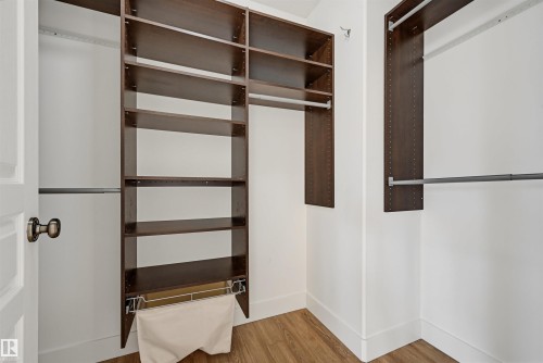 Custom closet system featuring dark wood-finish shelving and multiple hanging rods - 11539 75 Avenue, Edmonton, AB - Indoor