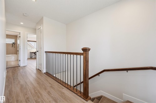Upper-level hallway featuring wood-finish flooring, recessed lighting, and a staircase with a wood handrail and wrought iron balusters - 11539 75 Avenue, Edmonton, AB - Indoor Photo Showing Other Room
