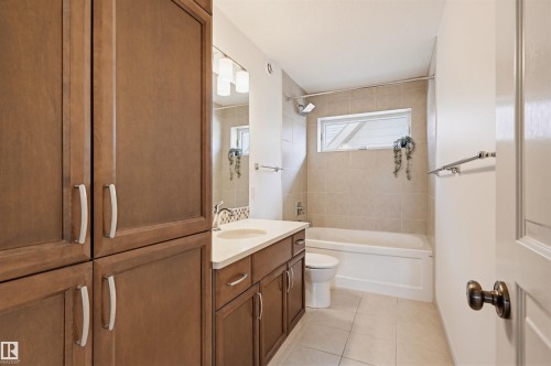 Bathroom featuring full-height wood-finish cabinetry, a single vanity with stone countertop, vessel sink, and chrome fixtures - 11539 75 Avenue, Edmonton, AB - Indoor Photo Showing Bathroom