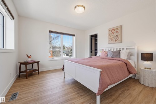 Bright interior space featuring wood-finish flooring, white walls, and a recessed closet with built-in shelving - 11539 75 Avenue, Edmonton, AB - Indoor Photo Showing Bedroom