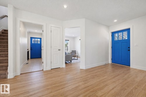 Entryway featuring wood-finish flooring, white trim, and a vibrant blue door with upper lites - 11539 75 Avenue, Edmonton, AB - Indoor Photo Showing Other Room