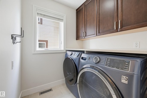 Laundry area featuring dark wood-finish cabinetry, a light-toned countertop, and light tile flooring - 11539 75 Avenue, Edmonton, AB - Indoor Photo Showing Laundry Room
