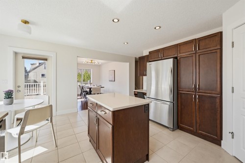 Kitchen featuring a central island with a light-toned countertop, tile flooring, rich wood-finish cabinetry, and recessed lighting - 11539 75 Avenue, Edmonton, AB - Indoor Photo Showing Kitchen