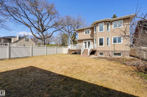 Spacious backyard featuring a multi-level deck, white vinyl fencing, and a two-story exterior with stone veneer accents - 11539 75 Avenue, Edmonton, AB - Outdoor