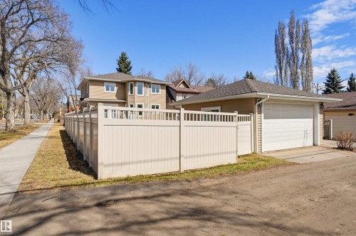 Detached two-story residence featuring tan siding, a dark shingle roof, and white-trimmed windows - 11539 75 Avenue, Edmonton, AB - Outdoor