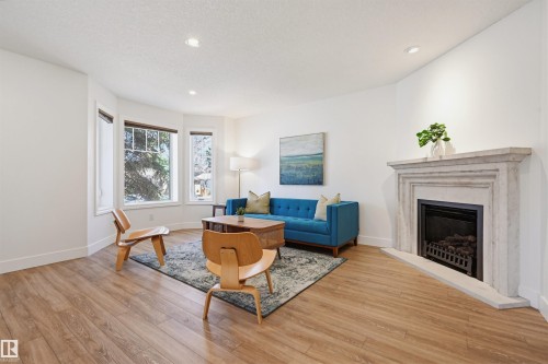 Living room featuring a decorative fireplace with a substantial mantel, recessed lighting, wood-finish flooring, and a bay window - 11539 75 Avenue, Edmonton, AB - Indoor Photo Showing Living Room With Fireplace