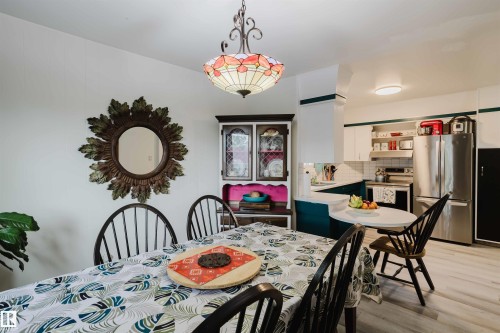 Dining area featuring a stained glass-style chandelier, wood-finish flooring, and a built-in hutch with glass-front cabinetry - 12026 104 Street, Edmonton, AB - Indoor Photo Showing Dining Room