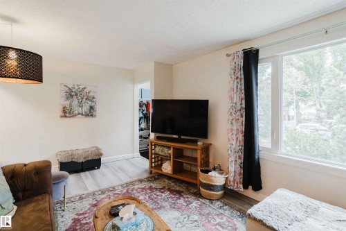 Living area featuring light wood-finish flooring, white baseboards, and a window with white trim - 12026 104 Street, Edmonton, AB - Indoor