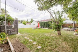 Expansive backyard featuring a large grassy area, stepping stone pathway, and mature trees - 
