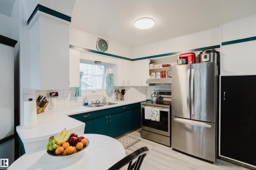 Kitchen featuring white upper cabinetry and teal lower cabinetry, white countertops, and white tile backsplash - 12026 104 Street, Edmonton, AB - Indoor Photo Showing Kitchen With Double Sink