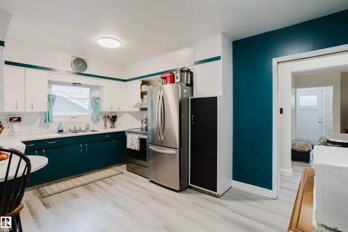 Kitchen featuring teal lower cabinetry, white upper cabinetry, and a white subway tile backsplash - 12026 104 Street, Edmonton, AB - Indoor Photo Showing Kitchen With Double Sink