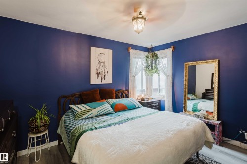Spacious room featuring a decorative ceiling fixture, dual windows, and wood-finish flooring - 12026 104 Street, Edmonton, AB - Indoor Photo Showing Bedroom