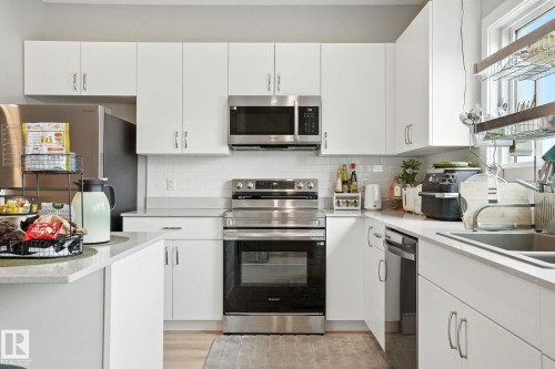 The kitchen features white cabinetry, stainless steel appliances, and light-colored countertops - 6260 175 Avenue, Edmonton, AB - Indoor Photo Showing Kitchen With Double Sink