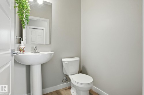 This bathroom features a pedestal sink with a chrome faucet, a white toilet, and light-toned walls - 6260 175 Avenue, Edmonton, AB - Indoor Photo Showing Bathroom