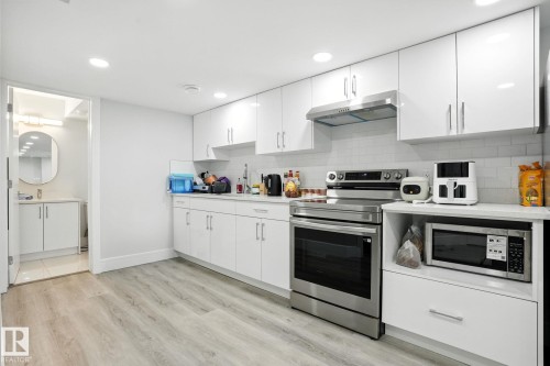 The kitchen features white cabinetry with stainless steel hardware, a stainless steel range with an overhead hood, and a white subway tile backsplash - 6260 175 Avenue, Edmonton, AB - Indoor Photo Showing Kitchen