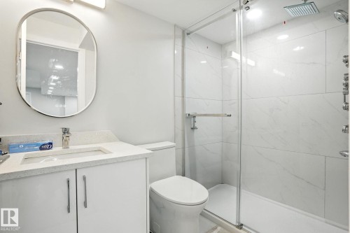 Bathroom featuring a white vanity with a light-colored countertop, an oval mirror, and a glass-enclosed shower with white tiled walls - 6260 175 Avenue, Edmonton, AB - Indoor Photo Showing Bathroom
