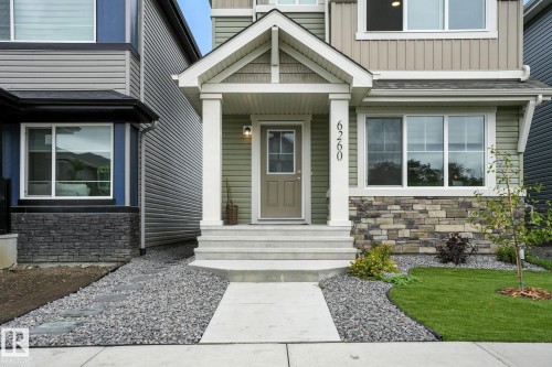 The property features a front entrance with a porch, a concrete walkway, and a yard with a lawn, landscaping stones, and a small tree - 6260 175 Avenue, Edmonton, AB - Outdoor With Facade