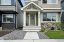 The property features a front entrance with a porch, a concrete walkway, and a yard with a lawn, landscaping stones, and a small tree - 6260 175 Avenue, Edmonton, AB  - Outdoor With Facade 