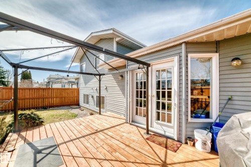 Spacious outdoor deck featuring natural wood planks, a metal pergola structure, and direct access through double French doors with multiple lites - 9845 184 Street, Edmonton, AB - Outdoor With Deck Patio Veranda With Exterior