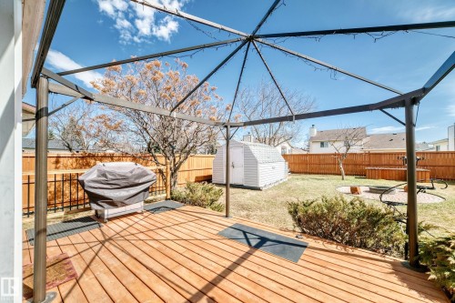 Expansive outdoor deck with a metal pergola structure, wood plank flooring, and a stone fire pit area - 9845 184 Street, Edmonton, AB - Outdoor With Deck Patio Veranda