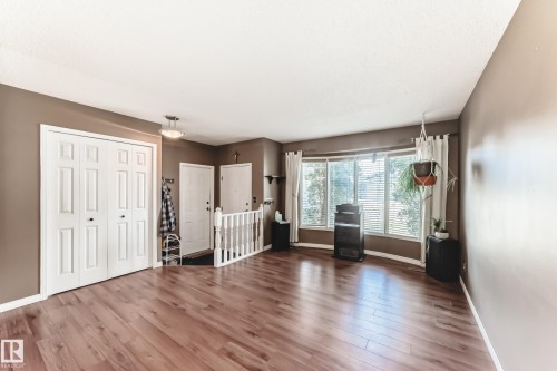 Spacious interior featuring wood-finish flooring, a large bay window, white trim, and a white balustrade - 9845 184 Street, Edmonton, AB - Indoor
