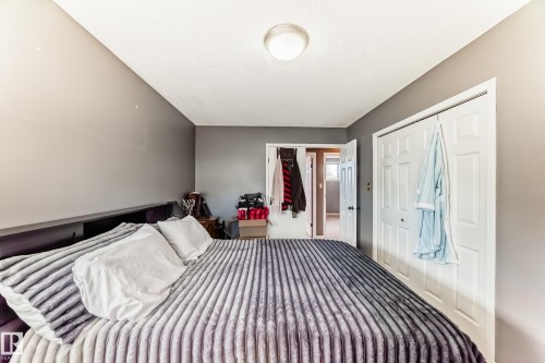 Carpeted bedroom featuring neutral-toned walls, a built-in closet with bi-fold doors, and a flush-mount ceiling light fixture - 9845 184 Street, Edmonton, AB - Indoor Photo Showing Bedroom