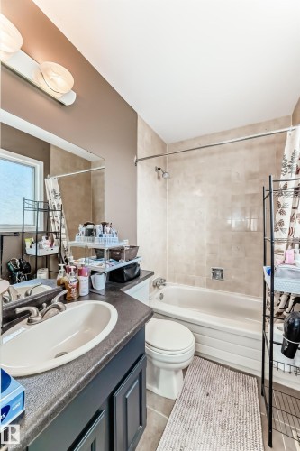 Bathroom featuring a single vanity with an integrated sink, dark countertop, and paneled cabinetry - 9845 184 Street, Edmonton, AB - Indoor Photo Showing Bathroom