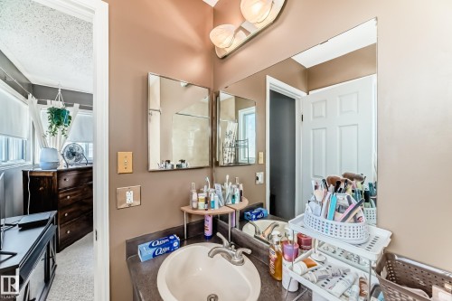 Bathroom vanity with an integrated sink, dark countertop, and overhead three-bulb light fixture - 9845 184 Street, Edmonton, AB - Indoor Photo Showing Bathroom