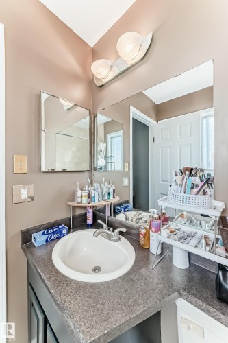 Bathroom vanity featuring a speckled countertop with an integrated white sink and brushed nickel faucet - 9845 184 Street, Edmonton, AB - Indoor Photo Showing Bathroom