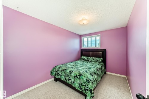 Room featuring textured ceiling, flush mount lighting fixture, window with white trim, and light-colored carpet flooring - 9845 184 Street, Edmonton, AB - Indoor Photo Showing Bedroom