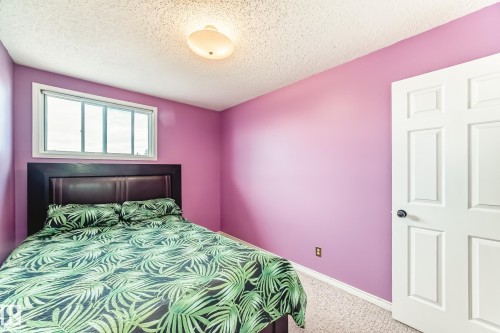 Bedroom featuring a multi-pane window, flush mount ceiling light, white paneled door, and textured ceiling - 9845 184 Street, Edmonton, AB - Indoor Photo Showing Bedroom