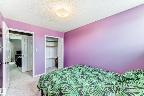Bedroom featuring purple walls, white trim, a built-in closet with bifold doors, and overhead lighting - 9845 184 Street, Edmonton, AB - Indoor Photo Showing Bedroom