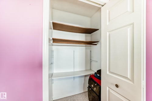 Built-in closet system featuring adjustable shelving, multiple storage levels, and a paneled white door with decorative hardware - 9845 184 Street, Edmonton, AB - Indoor Photo Showing Other Room